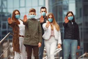 People wearing protective masks are showing stop sign by hands.